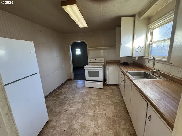 a kitchen with a sink a stove top oven and a refrigerator