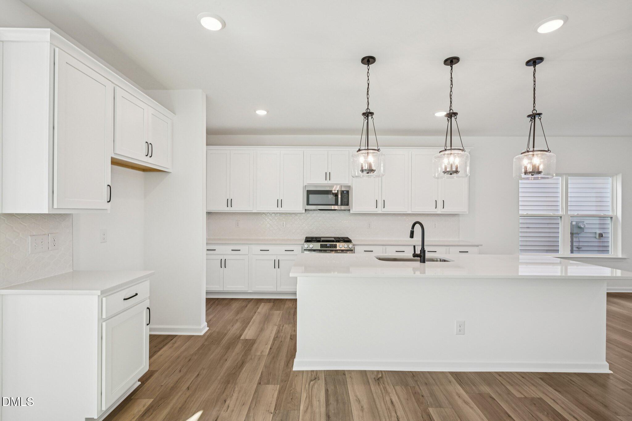 2840 Quarry Road, Unit 174 Rolesville, NC 27571 - Photo 12 of 32 a kitchen with stainless steel appliances granite countertop a sink a stove and a wooden floors