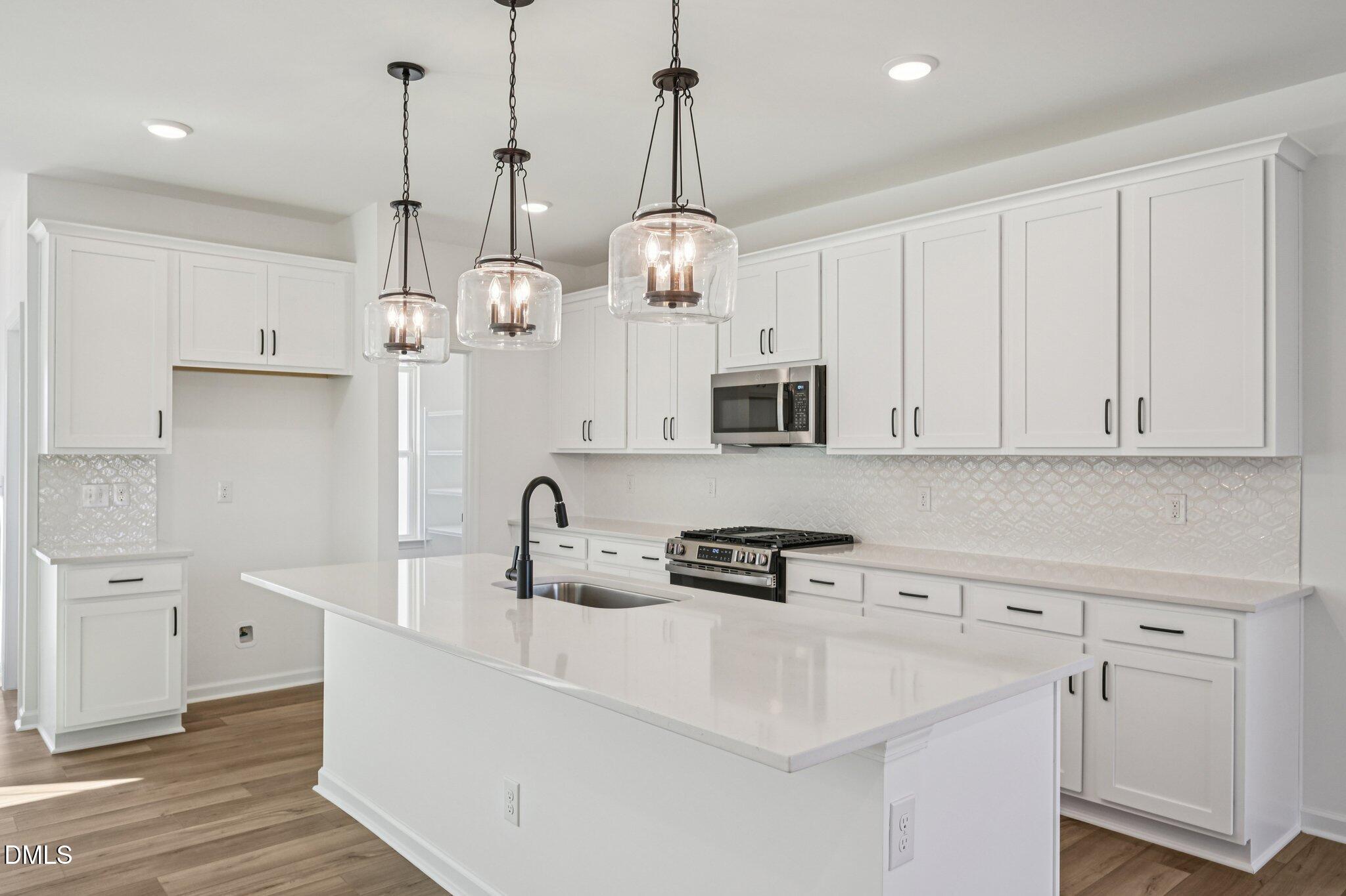 2840 Quarry Road, Unit 174 Rolesville, NC 27571 - Photo 13 of 32 a kitchen with stainless steel appliances a white cabinets and wooden floor