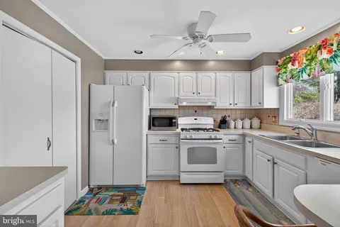 a kitchen with stainless steel appliances a sink cabinets and a window