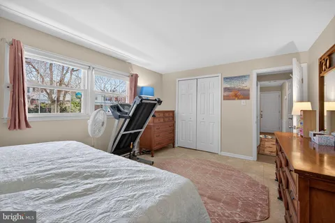 a bedroom with a bed a desk and large windows