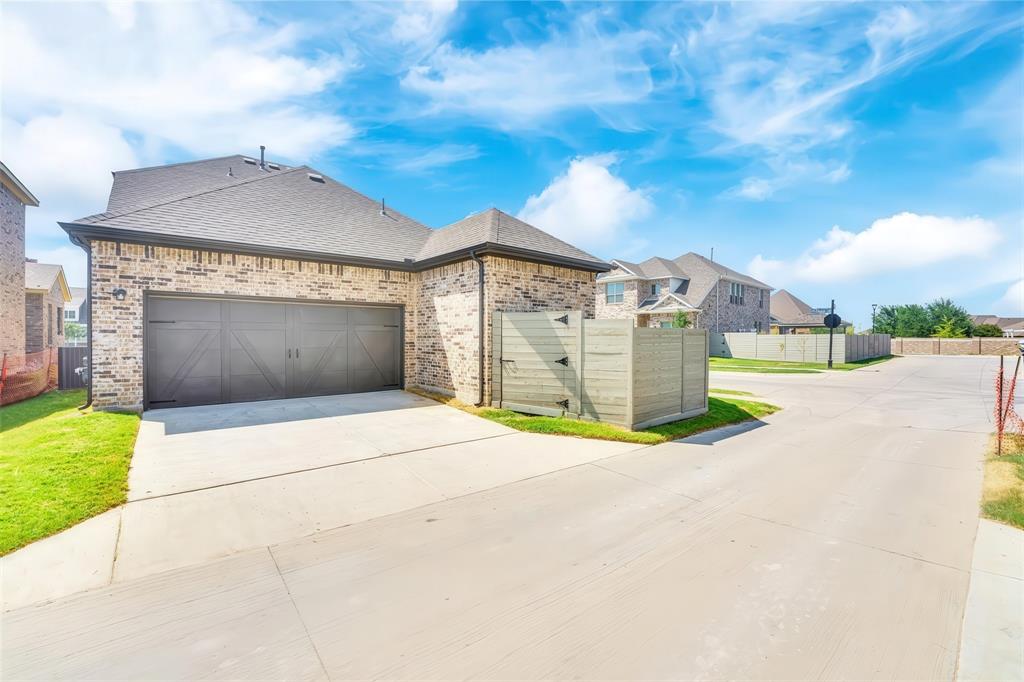 3610 Scotsman Road Sachse, TX 75048 - Photo 29 of 34 Brick exterior with a dark-toned garage door, concrete driveway, and slatted privacy fence