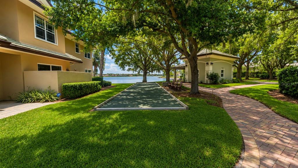 6552 Moorings Point Circle, Unit 102 Lakewood Ranch, FL 34202 - Photo 55 of 57 a view of a yard in front of a brick house with a large tree