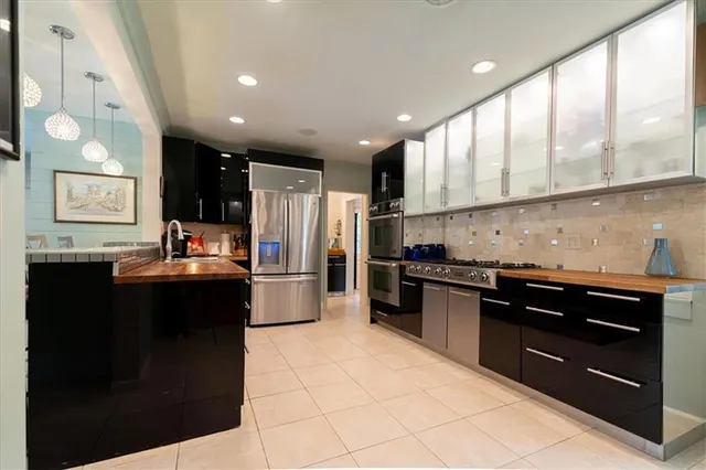 a kitchen with stainless steel appliances granite countertop a refrigerator a sink a stove and oven