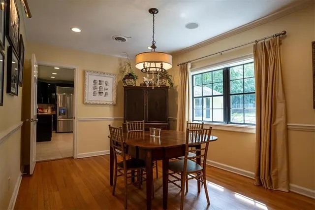 a dining room with wooden floor a chandelier a wooden table and chairs