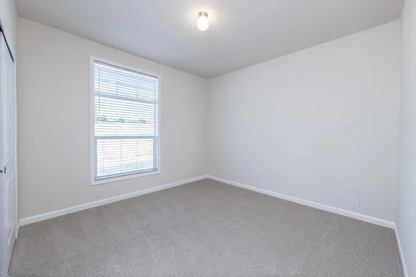 a view of an empty room with closet and a window