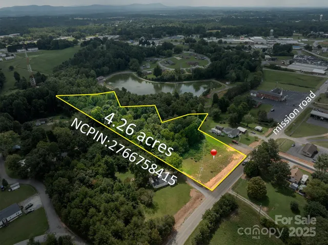 an aerial view of a residential houses with outdoor space and trees
