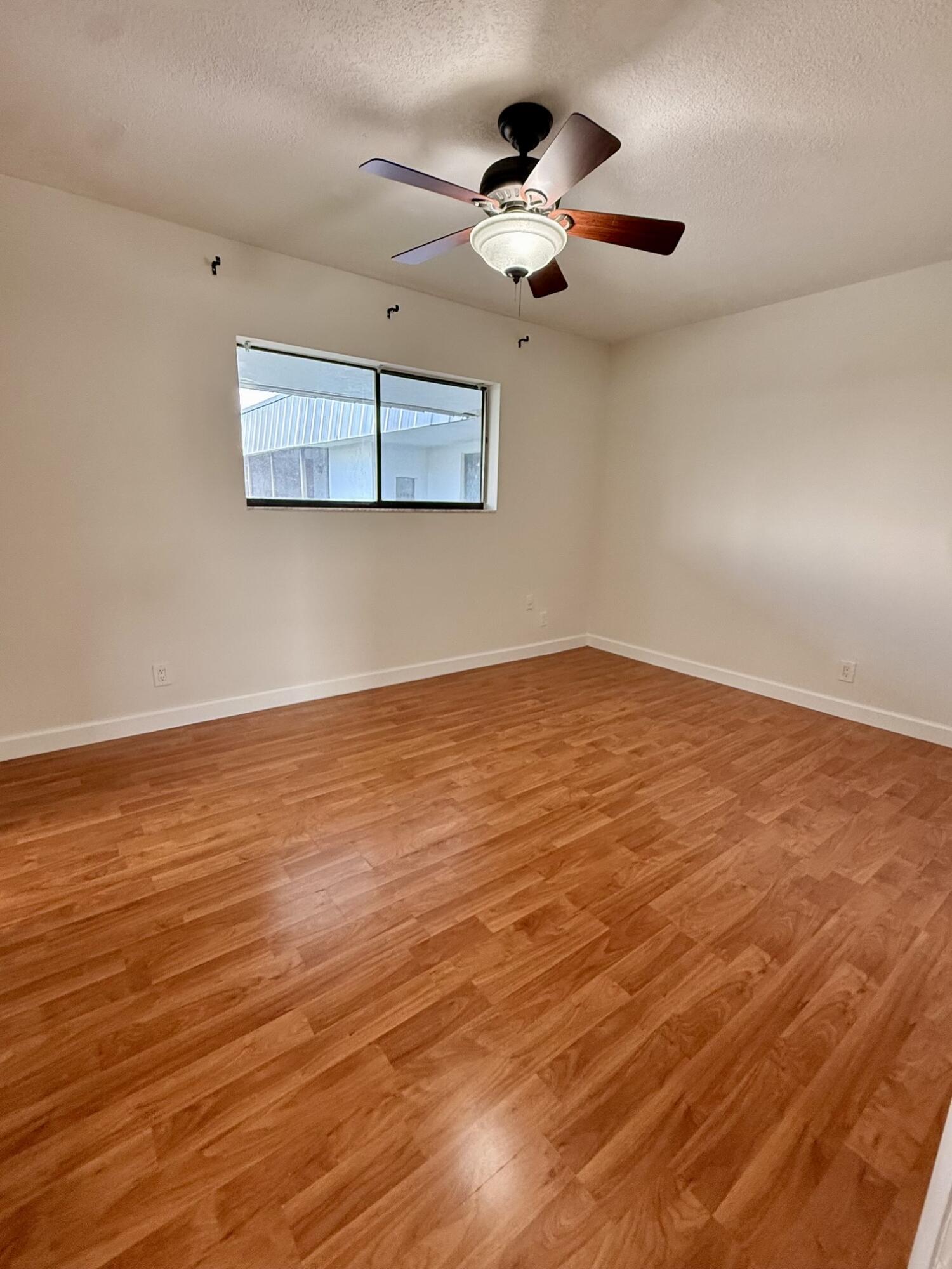 875 Northwest 13th Street, Unit 405 Boca Raton, FL 33486 - Photo 8 of 16 an empty room with wooden floor and ceiling fan