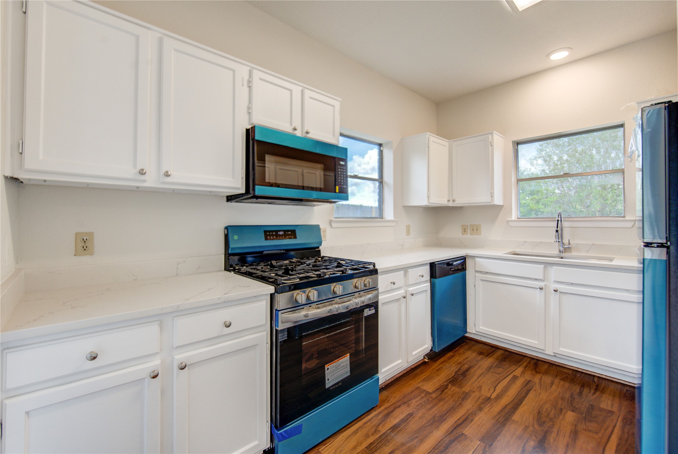 308 North Ranch House Road Angleton, TX 77515 - Photo 14 of 38 Bright and updated kitchen featuring white cabinetry, sleek countertops, and stainless steel appliances, including a gas range and built-in microwave.
