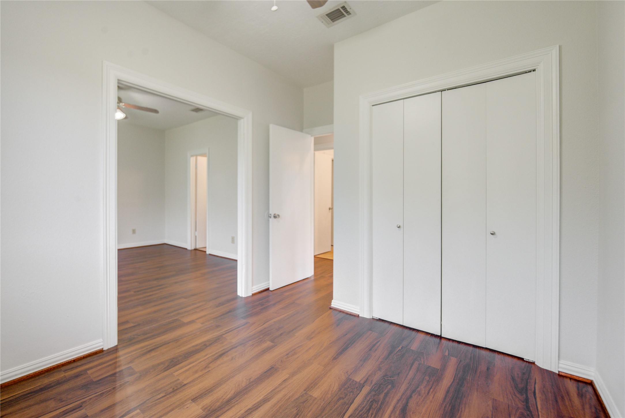 308 North Ranch House Road Angleton, TX 77515 - Photo 25 of 38 Bright and airy primary suite with large picture window overlooking the backyard, filling the space with natural light. The open layout seamlessly connects to an additional room, offering versatility for a study, workout space, or secondary bedroom setup.