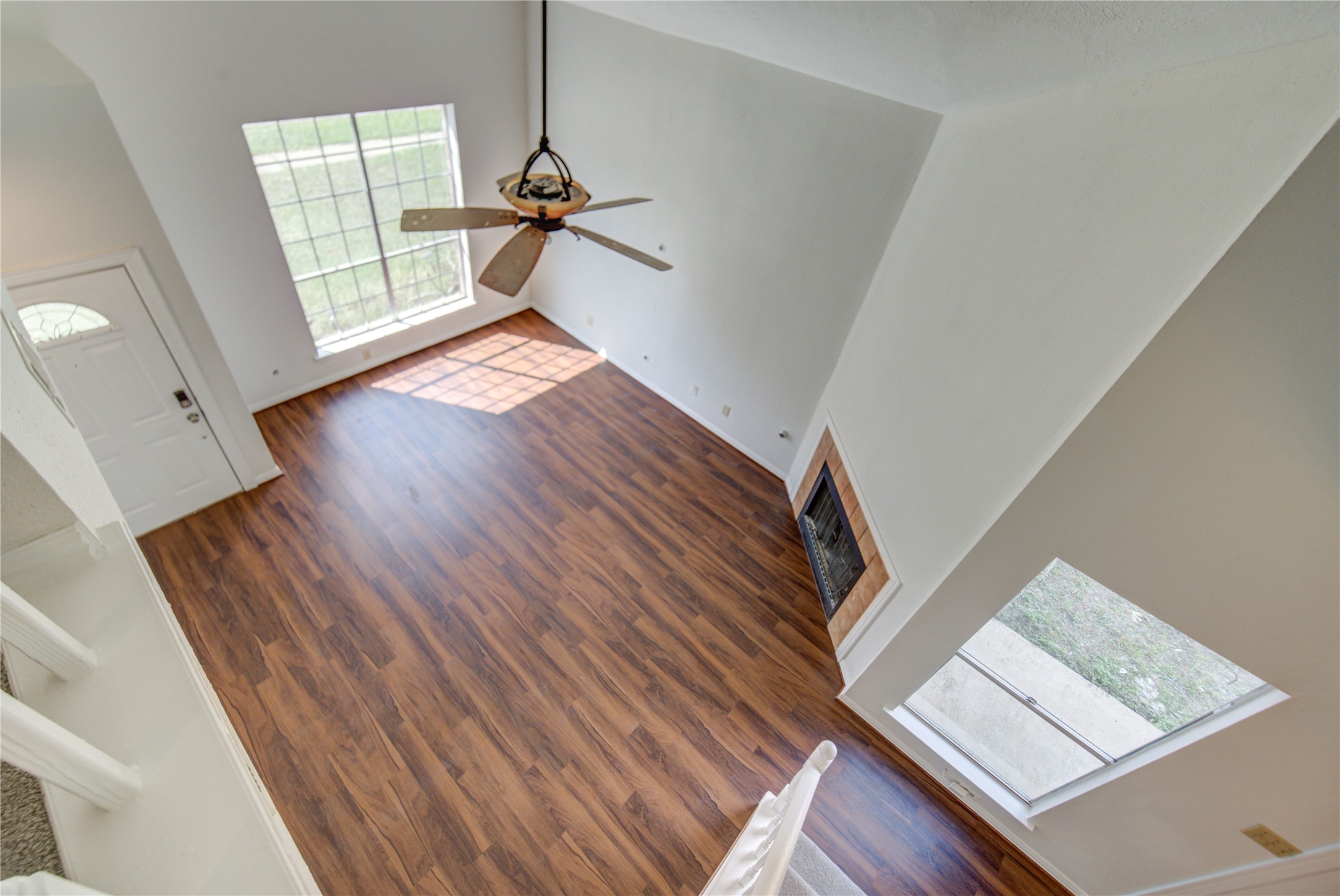 308 North Ranch House Road Angleton, TX 77515 - Photo 28 of 38 Stunning two-story living room viewed from above, showcasing soaring ceilings, expansive windows, and abundant natural light. The open layout highlights the spaciousness of the home, complete with a cozy fireplace and seamless flow to the main living areas.