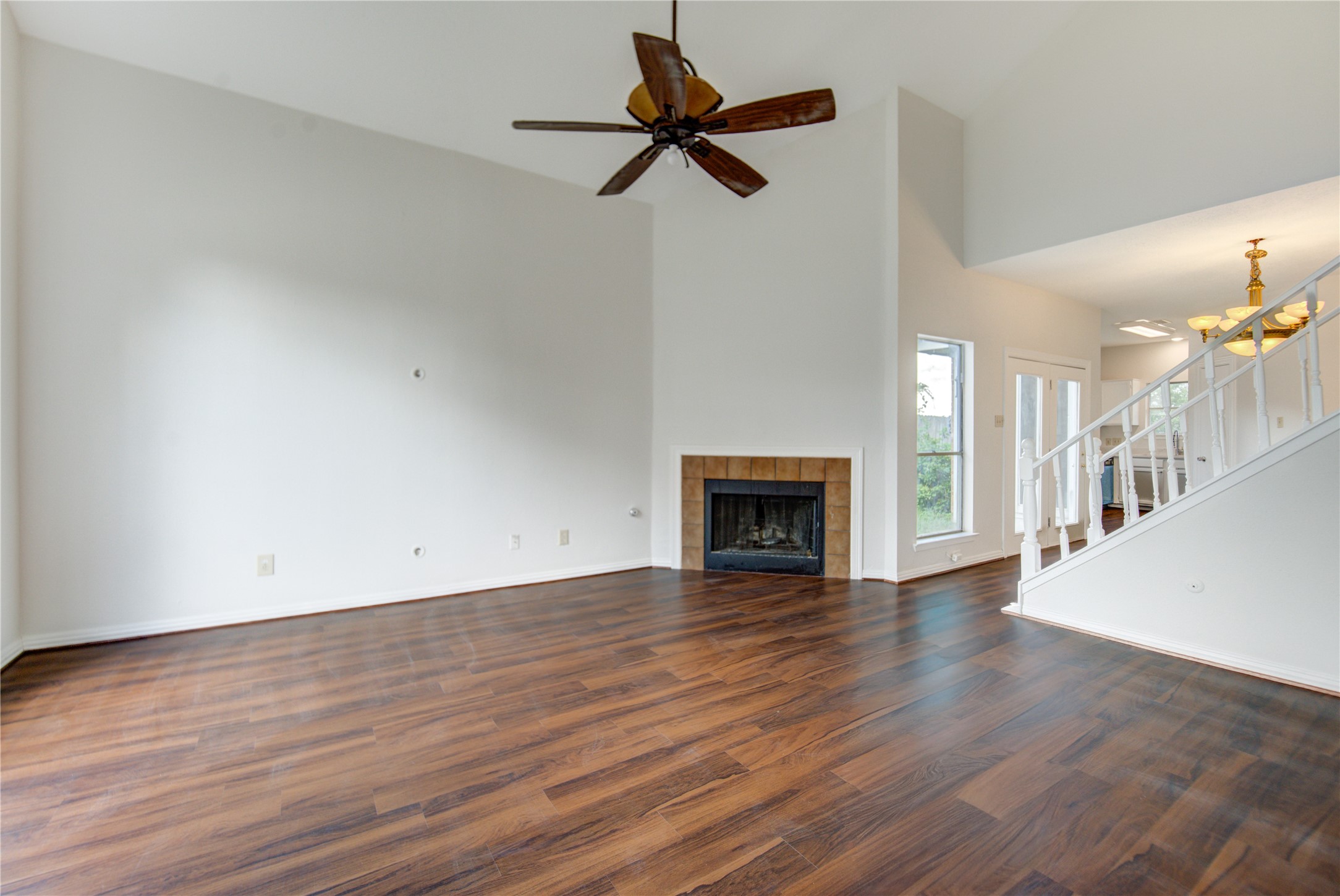 308 North Ranch House Road Angleton, TX 77515 - Photo 6 of 38 Expansive living area with high ceilings, modern flooring, and a cozy fireplace. The open-concept design seamlessly connects to the dining area and staircase, creating a warm and inviting atmosphere.