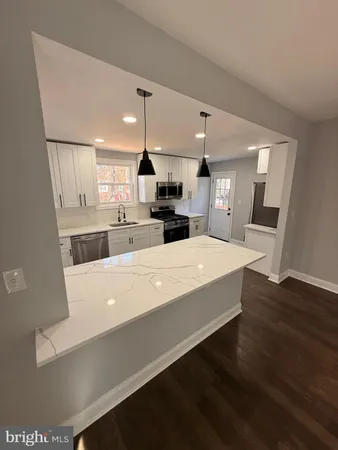a large white kitchen with wooden floors and stainless steel appliances
