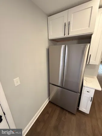 a view of a refrigerator in kitchen and an empty room