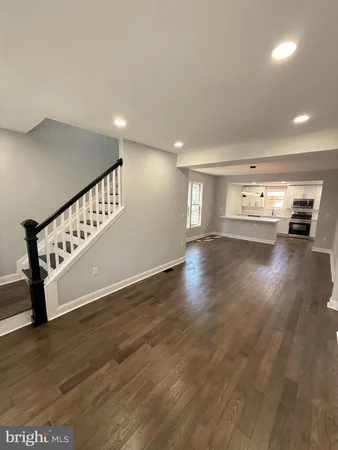 a view of an empty room with wooden floor and windows