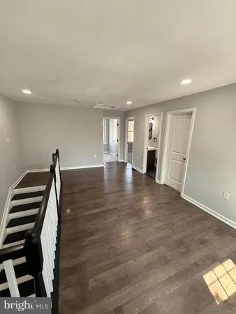 a view of an empty room with wooden floor and stairs
