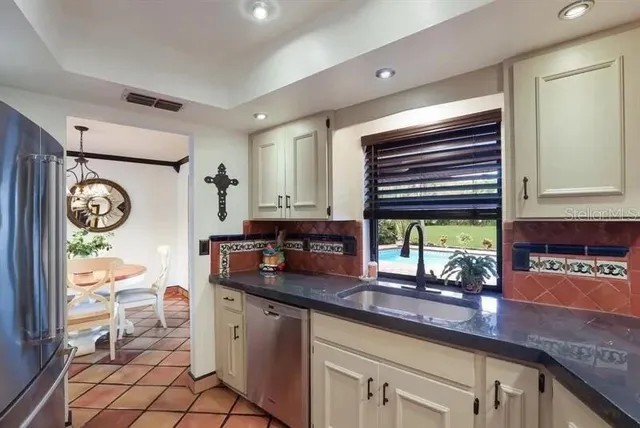 a kitchen with stainless steel appliances kitchen island granite countertop a refrigerator and a sink
