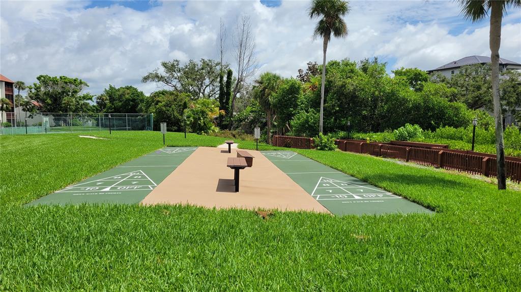 1626 Stickney Point Road, Unit 102 Sarasota, FL 34231 - Photo 40 of 42 a white bench sitting in the grass near a palm tree
