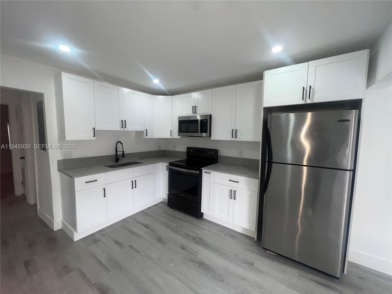 1800 Southwest 3rd Street, Unit D Miami, FL 33135 - Photo 6 of 27 a kitchen with a refrigerator a microwave a sink and cabinets