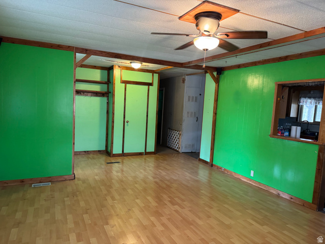 210 South State Street Moroni, UT 84646 - Photo 2 of 23 Spacious interior room featuring wood-finish flooring, vibrant green paneling, and an exposed wood beam ceiling