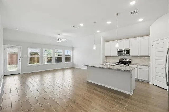 a kitchen with kitchen island granite countertop a sink cabinets and wooden floor
