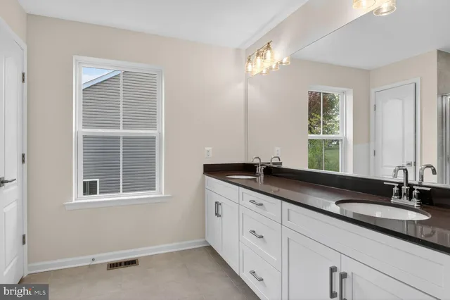 a bathroom with double sink and a window