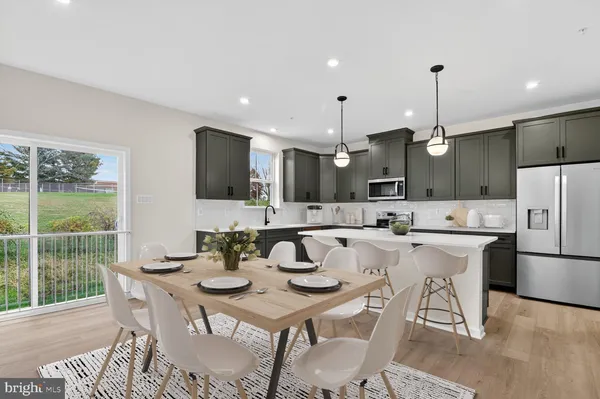 a kitchen with stainless steel appliances kitchen island granite countertop a dining table chairs and a refrigerator