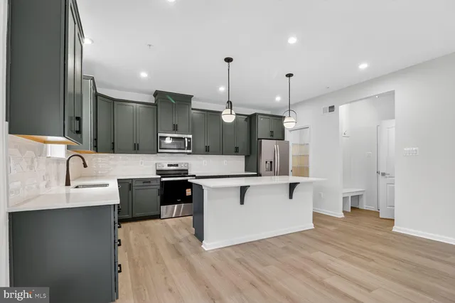 a kitchen with stainless steel appliances kitchen island granite countertop a sink stove and refrigerator