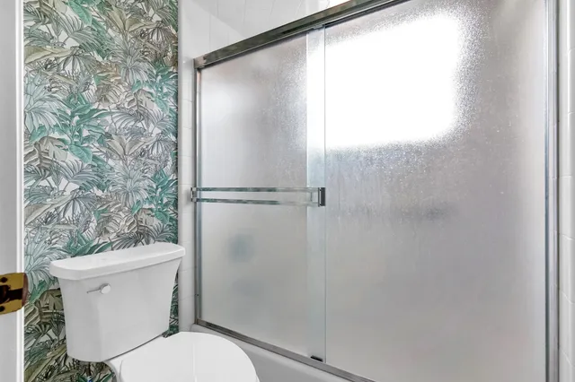 a white toilet sitting next to a shower