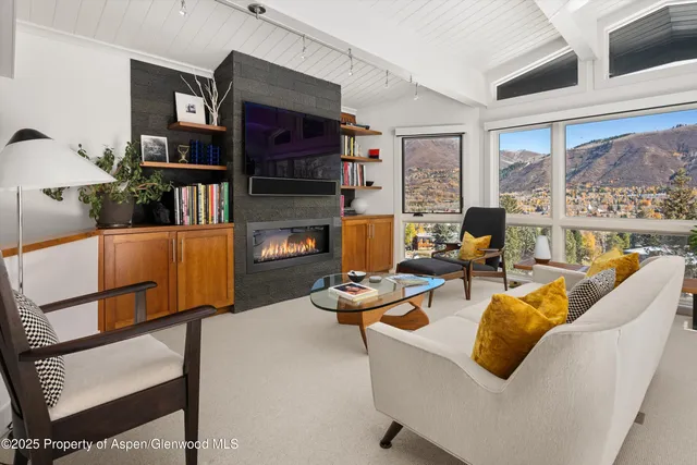a living room with furniture a flat screen tv and a large window