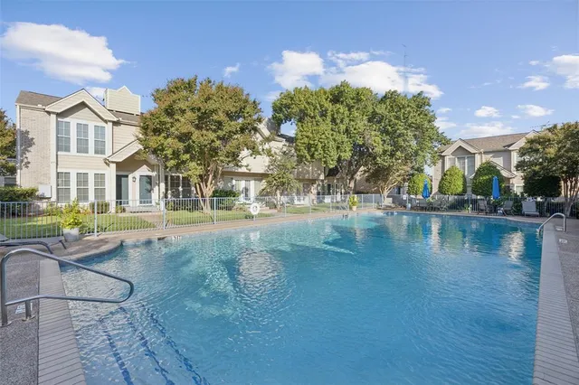 a view of pool with lawn chairs and large trees