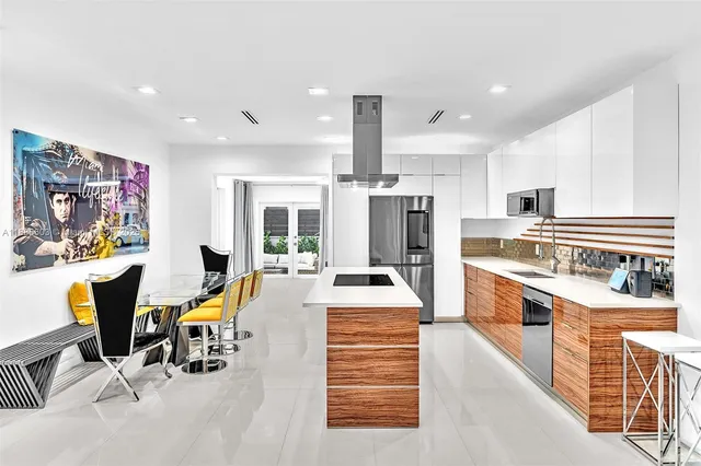 a kitchen with stainless steel appliances kitchen island granite countertop a table chairs in it and wooden floors