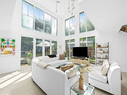 a living room with furniture a flat screen tv and a floor to ceiling window