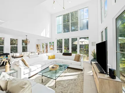 a living room with furniture a flat screen tv and a large window