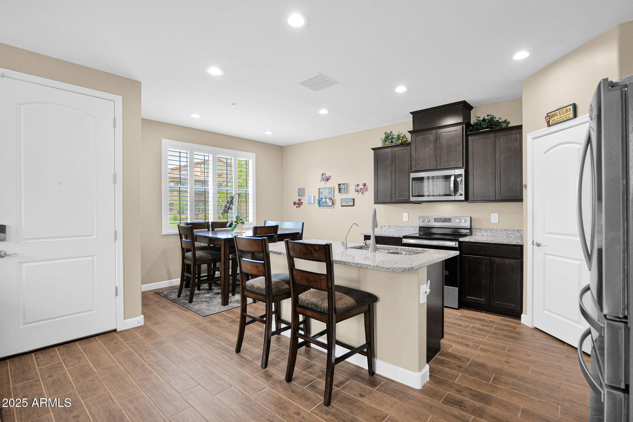 1255 North Arizona Avenue, Unit 1289 Chandler, AZ 85225 - Photo 4 of 32 a kitchen with stainless steel appliances granite countertop a stove a refrigerator a sink a dining table and chairs with wooden floor