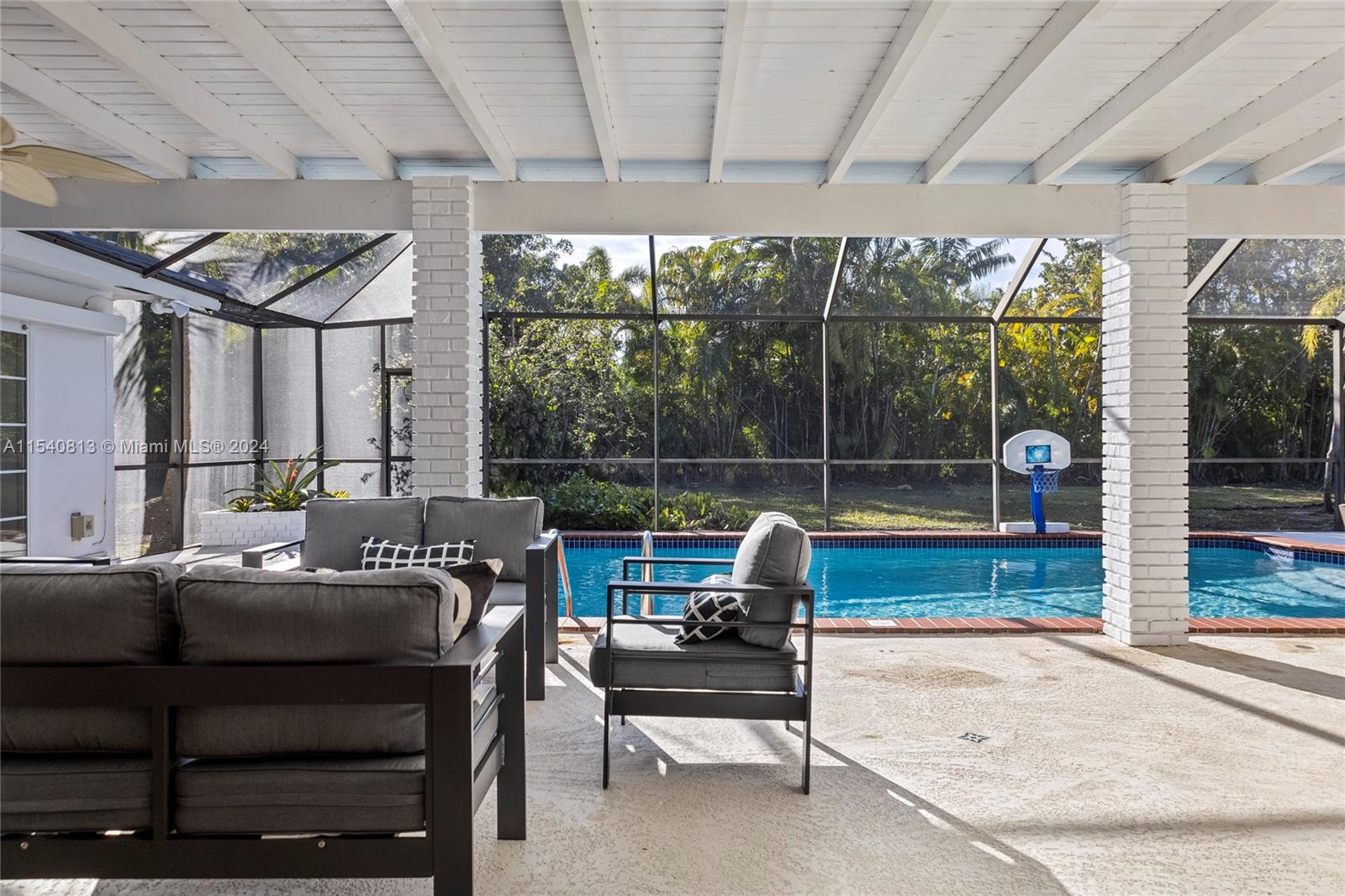 10130 Southwest 70th Avenue Pinecrest, FL 33156 - Photo 60 of 75 a living room with furniture a flat screen tv and a floor to ceiling window