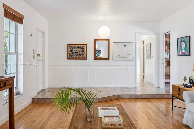 a view of a dining room with furniture one side kitchen view and wooden floor