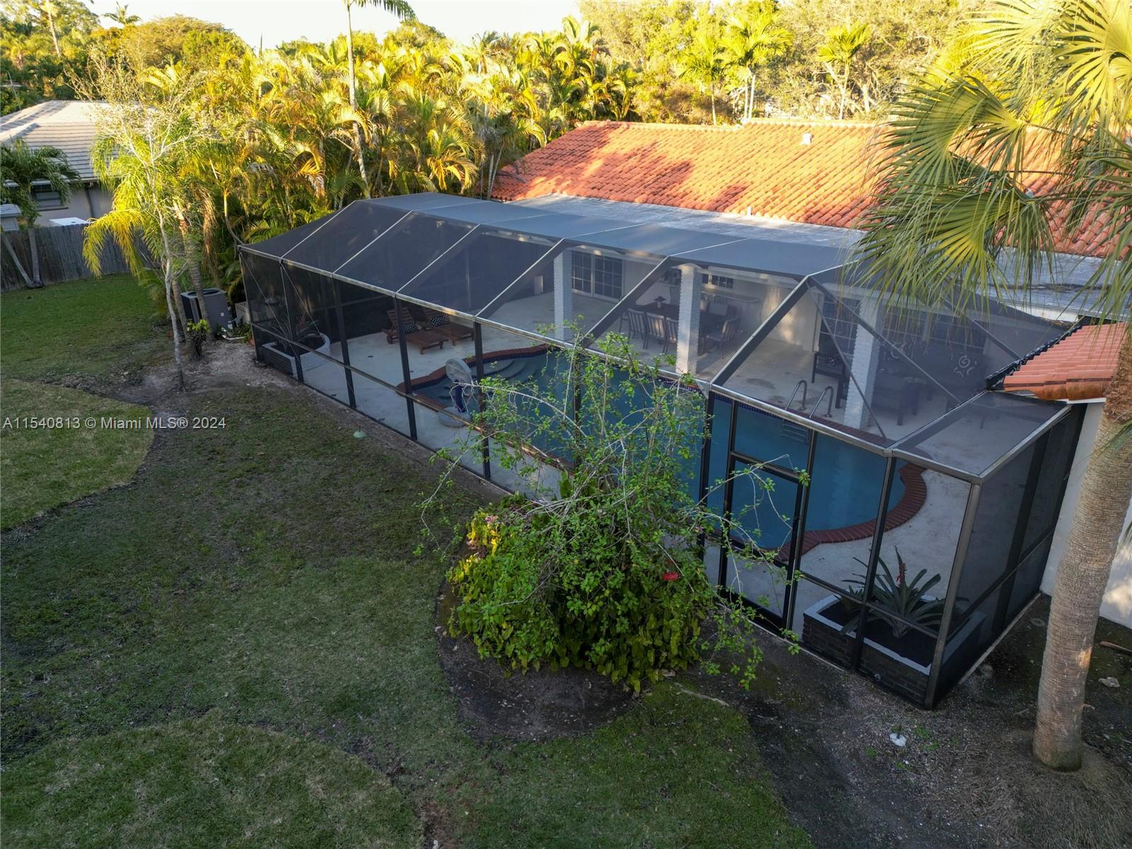 10130 Southwest 70th Avenue Pinecrest, FL 33156 - Photo 75 of 75 a backyard of a house with table and chairs under an umbrella