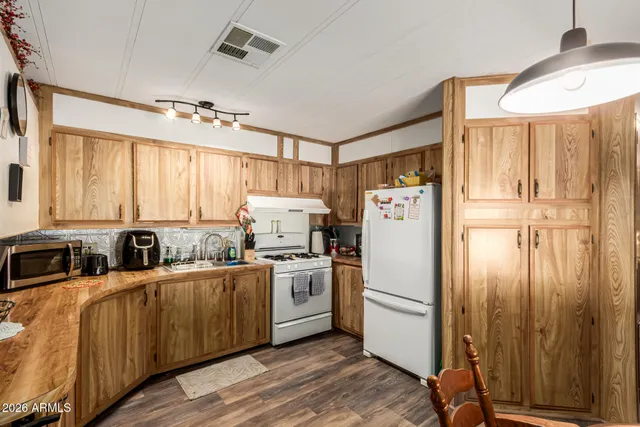 a kitchen with refrigerator a stove a sink and dishwasher with wooden floor