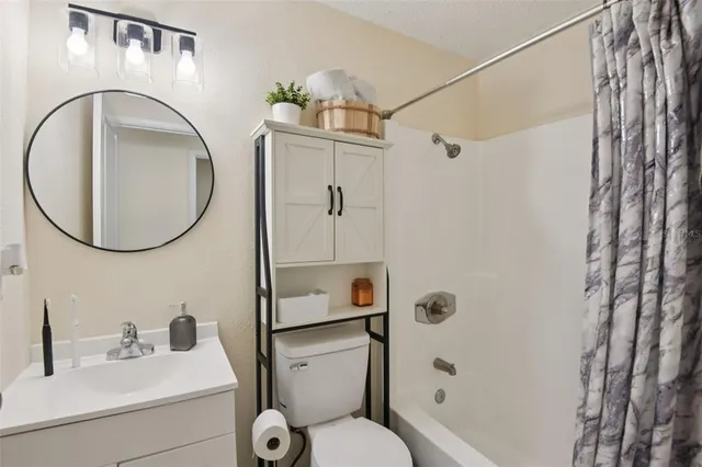 a bathroom with a toilet sink vanity tub and mirror