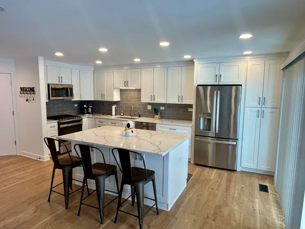 a kitchen with stainless steel appliances a refrigerator a stove a sink and a chairs