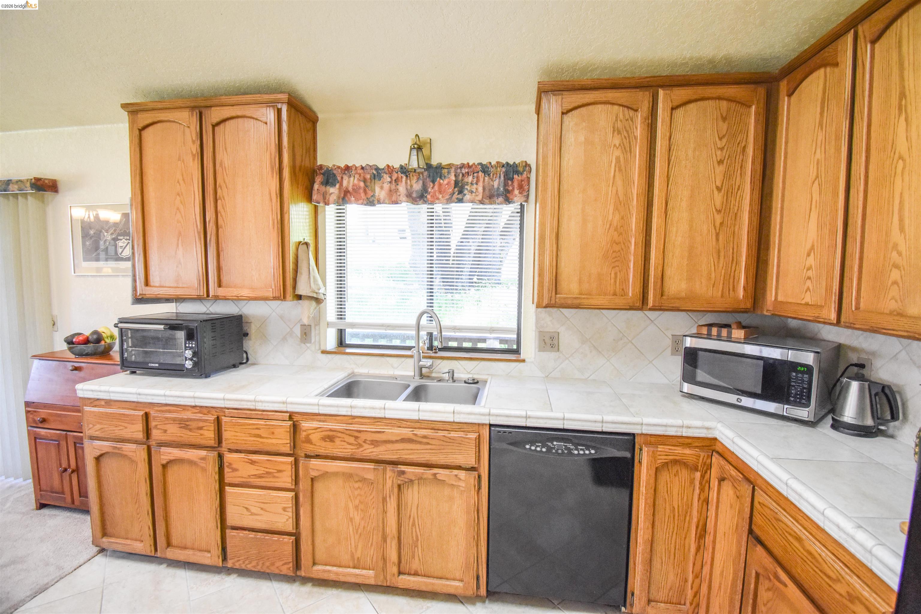 15170 Potato Ranch Road Sonora, CA 95370 - Photo 20 of 49 Kitchen with black dishwasher, tile counters, stainless steel microwave, and wood finish cabinetry