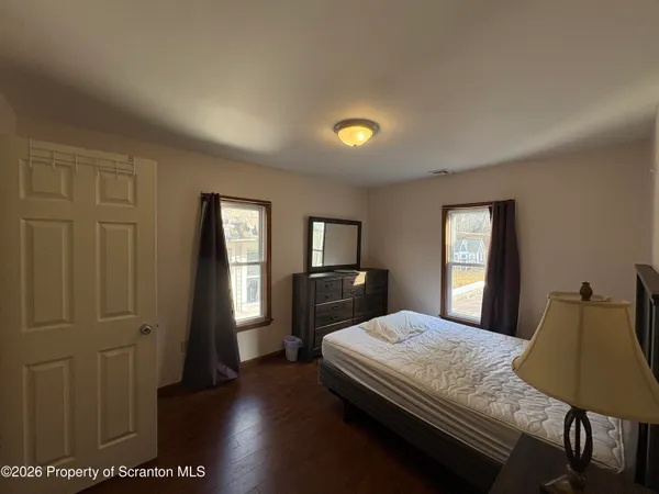 a bedroom with a bed a mirror on dresser and a window