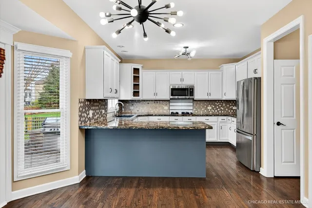 a kitchen with stainless steel appliances granite countertop white cabinets sink and window