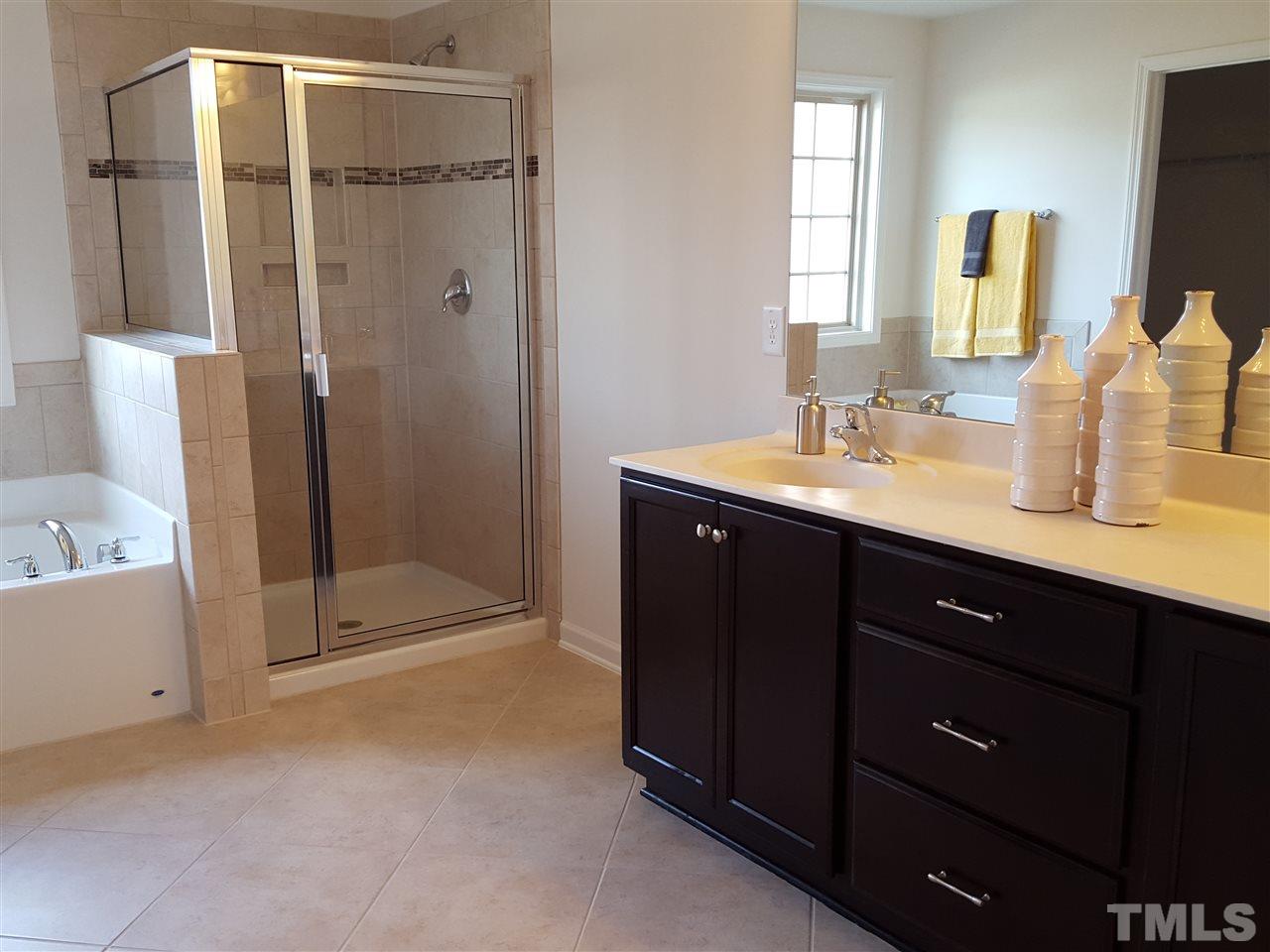 7633 Channery Way Raleigh, NC 27616 - Photo 17 of 25 a en suite bathroom with a double vanity sink a large mirror and shower