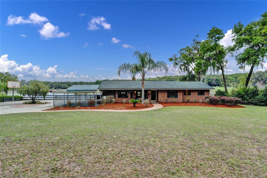 a view of a big house with a big yard and large trees