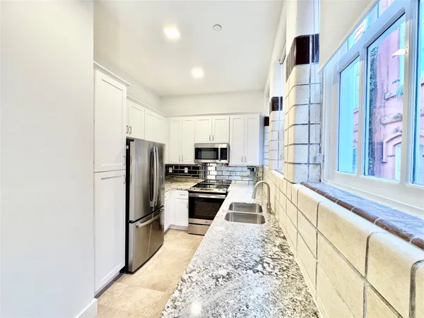 a kitchen with stainless steel appliances granite countertop a refrigerator a stove and a sink with wooden floor