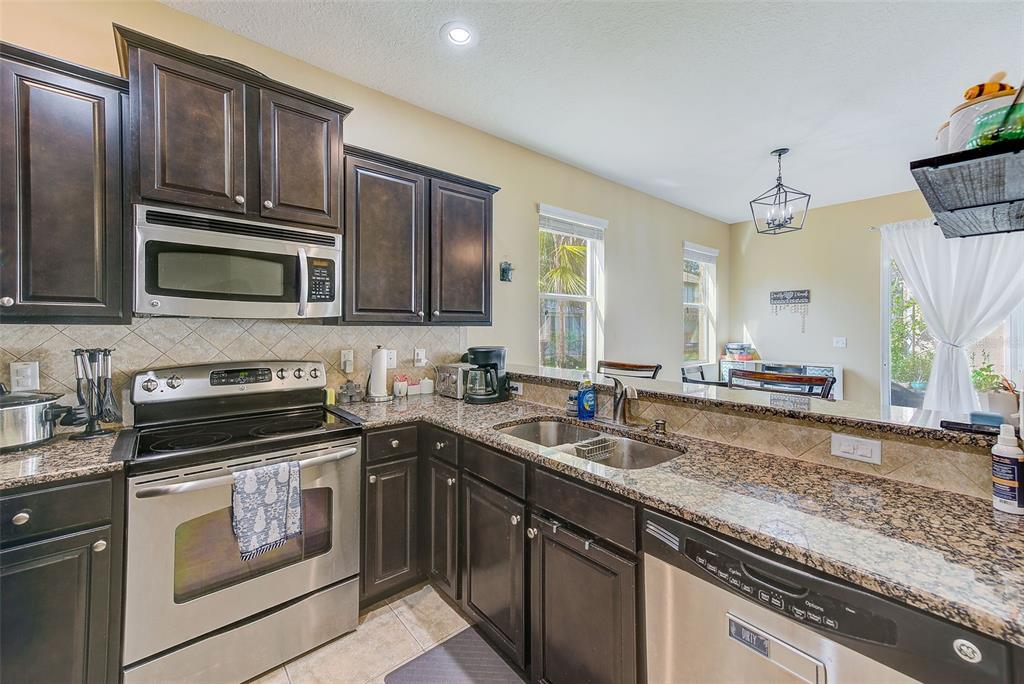 780 Spring Flowers Trail Brandon, FL 33511 - Photo 12 of 33 a kitchen with granite countertop a sink stove and microwave