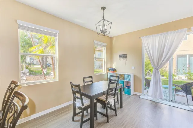 a kitchen with stainless steel appliances granite countertop a stove a refrigerator a sink a dining table and chairs with wooden floor