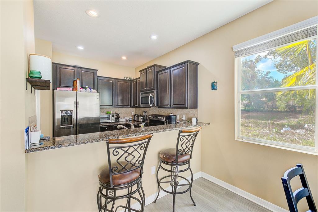 780 Spring Flowers Trail Brandon, FL 33511 - Photo 8 of 33 a kitchen with stainless steel appliances granite countertop a stove a refrigerator a sink a dining table and chairs with wooden floor